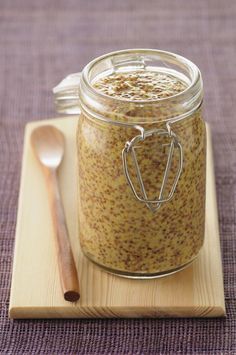 a jar filled with food sitting on top of a wooden cutting board next to a spoon