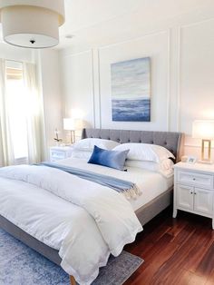 a large white bed sitting in a bedroom on top of a hard wood floor