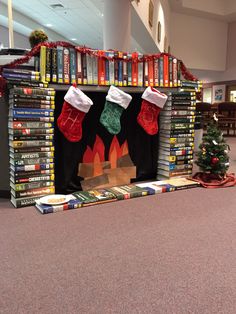 a christmas display with stockings and stockings hanging from the fireplace in front of bookshelves