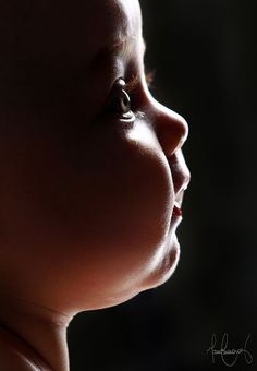 a close up of a child's face with the sun shining on her head