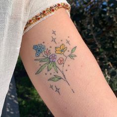 a woman's arm with flowers and stars tattooed on the left side of her arm