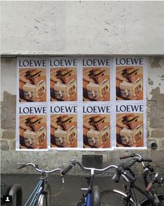 two bicycles parked next to each other in front of a wall with posters on it