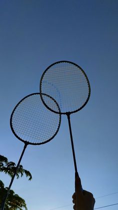 two tennis racquets being held in the air by someone's hand