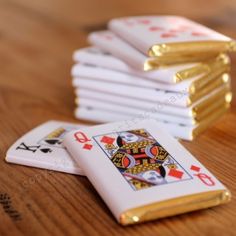 a stack of playing cards sitting on top of a wooden table next to gold foil