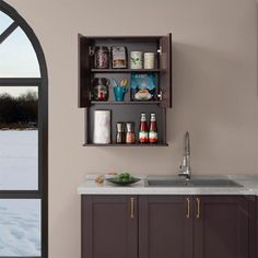 a kitchen with an arched window, sink and cabinets filled with drinks on the counter