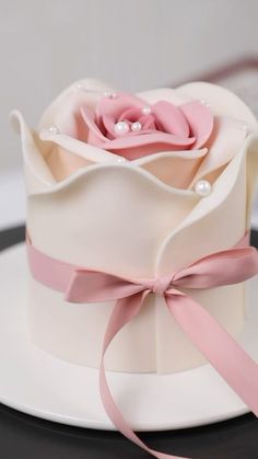 a white cake with pink flowers and pearls on it's top, sitting on a plate