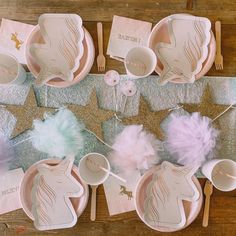 a table set up with pink and gold unicorn plates, napkins, cups, and utensils