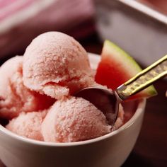 a bowl filled with pink ice cream next to a slice of watermelon