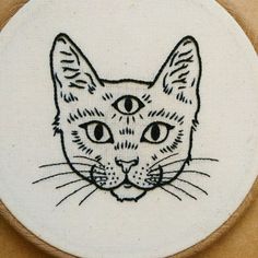 a close up of a cat embroidered on a piece of cloth with the image of a cat's face