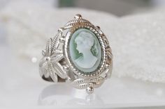 CAMEO RING, Green Emerald Cameo Ring, Victorian Style Antique Silver Filigree Ring, Flower Ornament Ring, Christmas Gift for her for women, Details of item: Metal: Silver plated or 24 k gold plated Gemstone: acrylic cameo Front Size: 10*14 mm The ring will be packed in a gift box. , FOR MATCHING NECKLACE: https://www.etsy.com/il-en/listing/248816663/victorian-green-toggle-cameo-necklace FOR MY RINGS COLLECTION HERE: https://www.etsy.com/il-en/shop/rebekajewelry?ref=seller-platform-mcnav&sect Silver Cameo Rings For Wedding, Silver Cameo Wedding Rings, Elegant Silver Cameo Rings, Antique Cameo Jewelry, Gold Ear Climbers, Ear Crawler Earrings, Ring Flower, Rose Quartz Earrings, Cameo Jewelry