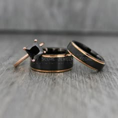 two black and gold wedding rings with an arrow in the middle