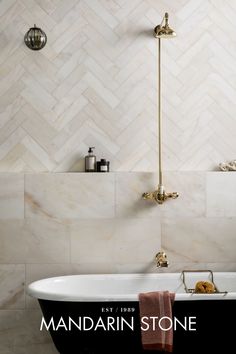 a bath tub sitting next to a shower head in a bathroom with white and black tile