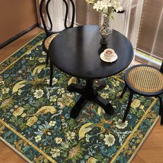 a black table with two chairs and a vase on top of it next to a rug