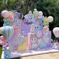 an outdoor birthday party with balloons and unicorns on the wall, including presents for children