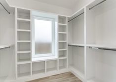 an empty walk in closet with white shelving