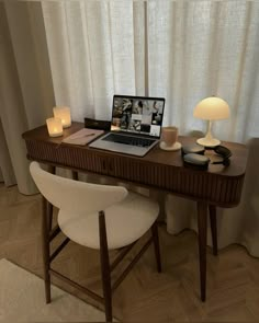 a laptop computer sitting on top of a wooden desk next to a lamp and chair