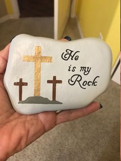 a hand holding a rock with a cross painted on it that says, no is my rock