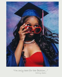 a woman wearing red glasses and a graduation cap with her hands to her face while she is looking at the camera