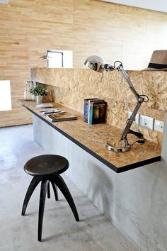 a desk with a lamp and books on it in a room that has wooden walls