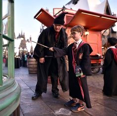 two young boys dressed in harry potter outfits and holding wands, standing next to each other