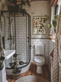 a white toilet sitting next to a shower in a bathroom on top of a hard wood floor