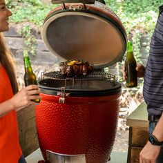 two people standing next to each other near a bbq with beer bottles on it