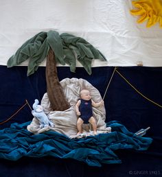 a baby doll sitting on top of a bed next to a palm tree and other items