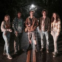 four people standing on the side of a road at night