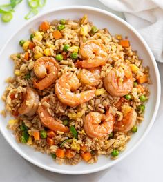 rice with shrimp and peas in a white bowl on a marble countertop next to a napkin