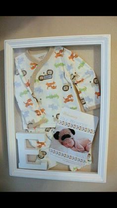 a baby's photo in a shadow box is shown with its clothes and booties