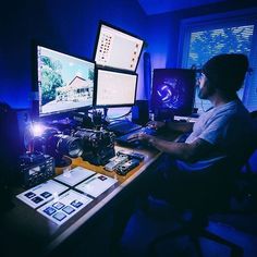 a man sitting at a desk in front of three computer monitors with cameras on it