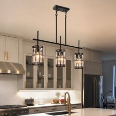 a kitchen with three lights hanging from the ceiling and an island in front of it