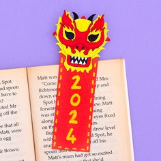 a red bookmark with a yellow dragon on it sitting next to an open book