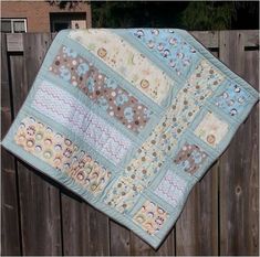 a baby quilt hanging on a wooden fence