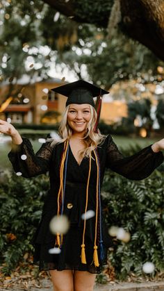 a woman in a graduation cap and gown is throwing confetti into the air