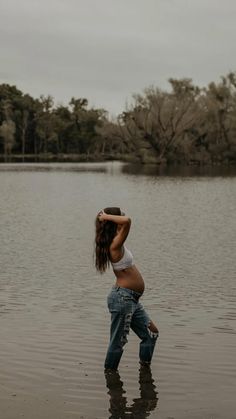 a woman standing in the water with her hands behind her head