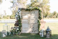 an outdoor ceremony setup with white flowers and greenery on the wall, candles and lanterns