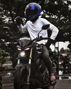 a man riding on the back of a motorcycle wearing a blue helmet and black gloves