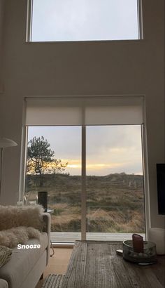 a living room with large windows looking out at the countryside outside in the evening time