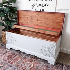 a white bench with a wooden box on top and a plant in the corner next to it