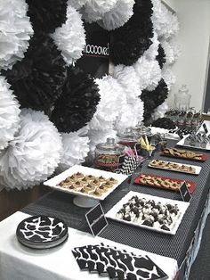 a table topped with lots of desserts and pastries next to a giant paper flower wall