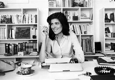 a woman sitting at a desk in front of bookshelves