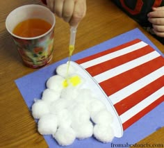 a child is painting an american flag with white cotton balls on a blue piece of paper