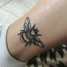 a small black and white bee tattoo on the arm