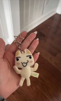 a hand holding a keychain with a cartoon cat on it's thumb