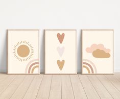 three art prints with hearts, sun and clouds on them in neutral colors against a white wall