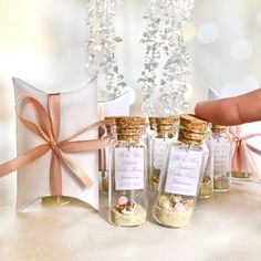 a hand holding a bottle filled with sand next to other small glass bottles and boxes