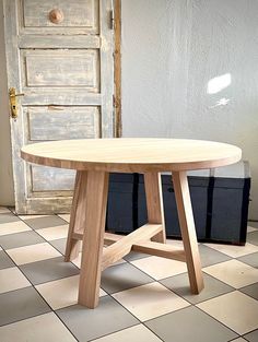 a wooden table sitting on top of a checkered floor next to a white door