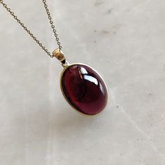 ITEM DESCRIPTION: >> The Pendant is made from Solid 14K Yellow Gold. Gemstone used is absolutely natural and ethically sourced. >> Natural Garnet in cabochon cut and oval shape with bezel setting is studded on it with utmost precision. >> This is a minimalist design and is absolutely hassle-free and everyday jewelry. Gem: Garnet Gem size: 14x19 mm oval Gem weight: 20.66 carats Gold purity: 14K (58.33% approx.) Gold weight: 0.62 grams Gross weight: 4.75 grams The Gold purity is guaranteed and it Garnet Necklace Vintage, Garnet Pendant Necklace, Gold Garnet Jewelry With Bezel Setting, Elegant Gold Cabochon Gemstones, 14k Gold Gemstones With Bezel Setting For Gift, Elegant Amber Oval Cabochon Necklace, Gift Oval Cabochon Necklace With Polished Finish, Elegant Red Cabochon Gemstones, Fine Jewelry Cabochon Gemstone Pendant