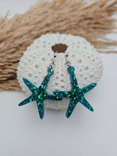 Add a touch of the ocean to your outfit with these stunning starfish earrings! These lightweight earrings are perfect for summer and will make you feel like you're under the sea, wherever you go. The sparkly glitter adds a touch of glamour to these tropical earrings, making them the perfect beach jewelry accessory. These shell earrings are a lovely gift for her, ideal for anyone who loves coastal jewelry and all things beach-related. Embrace the summer vibes with these beautiful ocean earrings t Ocean-inspired Starfish Charm Earrings, Nickel-free Starfish Earrings Ocean-inspired, Handmade Ocean-inspired Star Earrings, Ocean-inspired Star Earrings For The Beach, Ocean-inspired Star Earrings For Beach, Star-shaped Ocean-inspired Earrings For Beach, Starfish Charm Earrings Gift, Starfish Charm Earrings For Gift, Gift Starfish Charm Earrings